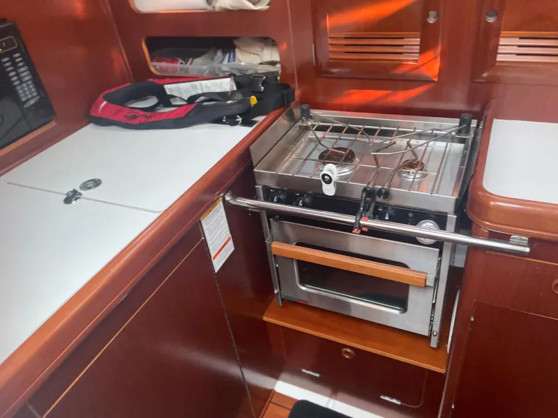 Slide: The Image of Beneteau 393 2002 model yacht kitchen with stove and storage compartments. - 11
