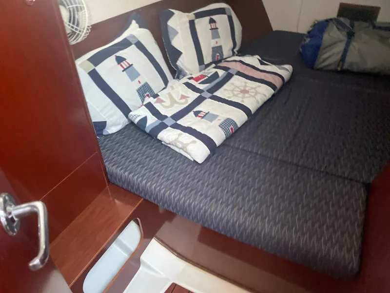 Slide: The Image of Cozy cabin bed in a 2002 Beneteau 393 sailboat with nautical-themed bedding. - 13