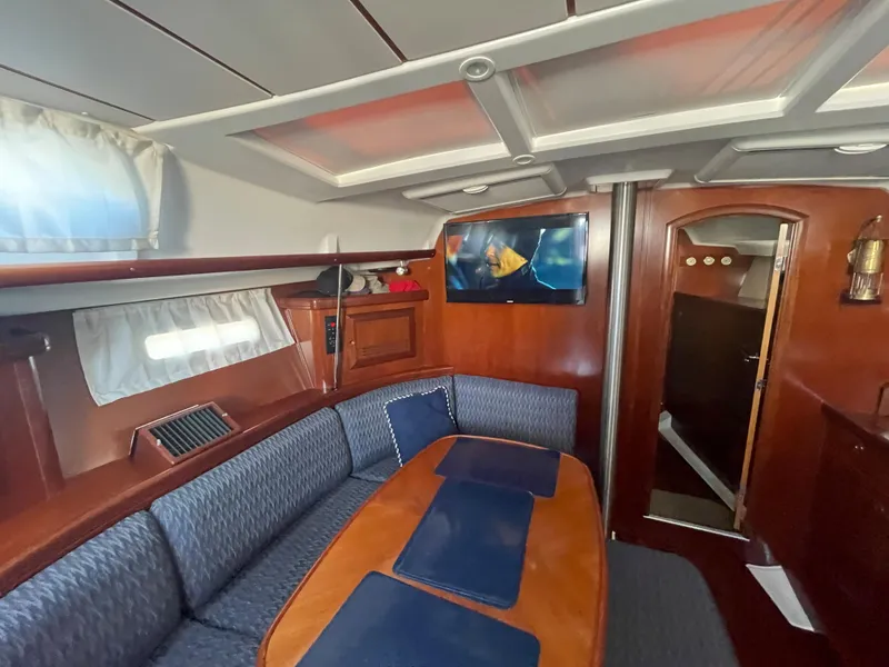 Slide: The Image of Interior of 2002 Beneteau 393 sailboat with dining area and TV. - 16