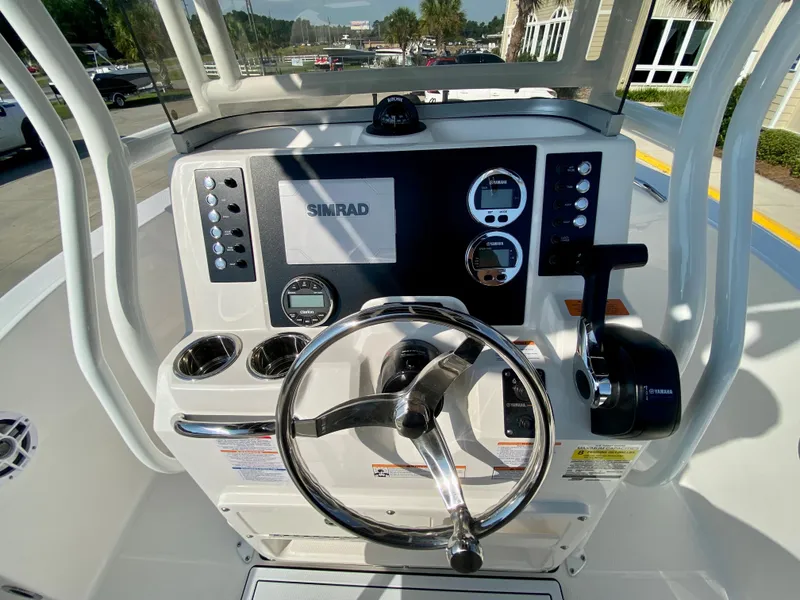 Slide: The Image of 2024 Robalo R180 Center Console boat dashboard with steering wheel and Simrad electronics. - 10