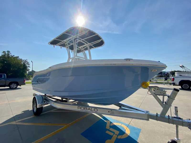 Slide: The Image of 2024 Robalo R180 Center Console boat on a trailer in a parking lot. - 1