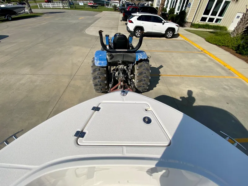 Slide: The Image of 2024 Robalo R180 Center Console boat being towed by a blue tractor in a parking lot. - 18
