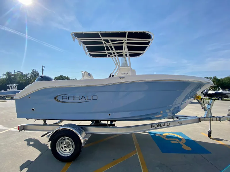 Slide: The Image of 2024 Robalo R180 Center Console boat on a trailer in a parking lot. - 20