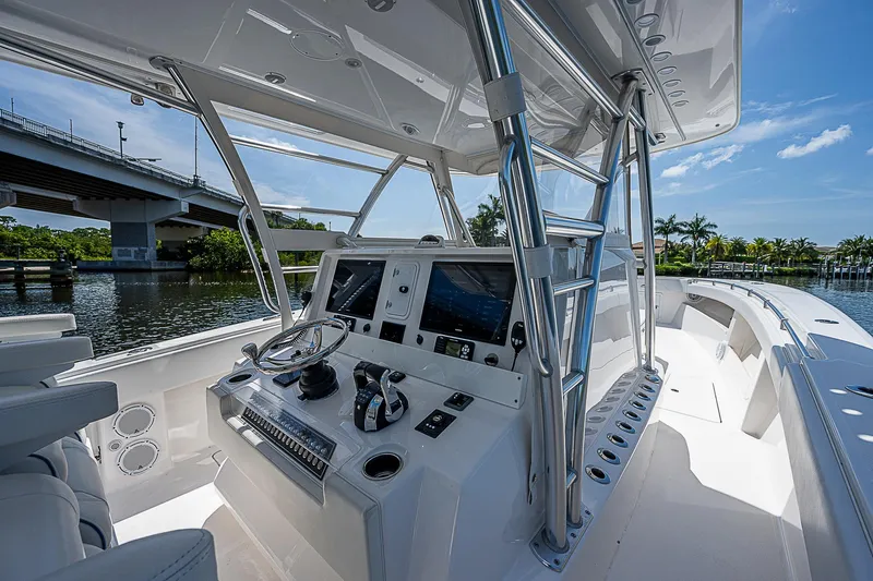 Slide: The Image of 2018 Invincible 42 boat cockpit with modern controls, docked near a bridge and palm trees. - 5
