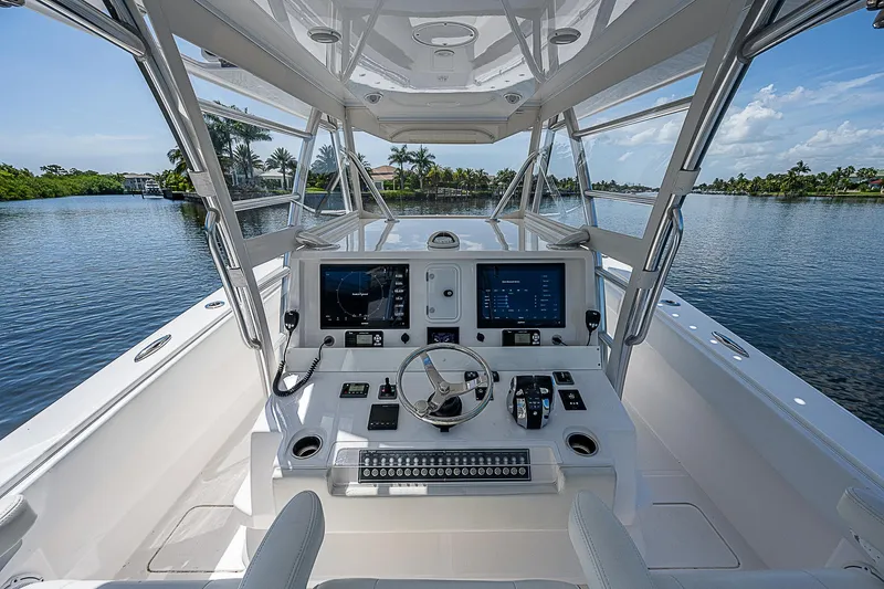 Slide: The Image of Invincible 42 boat cockpit with modern controls, navigating serene waters, 2018 model. - 6