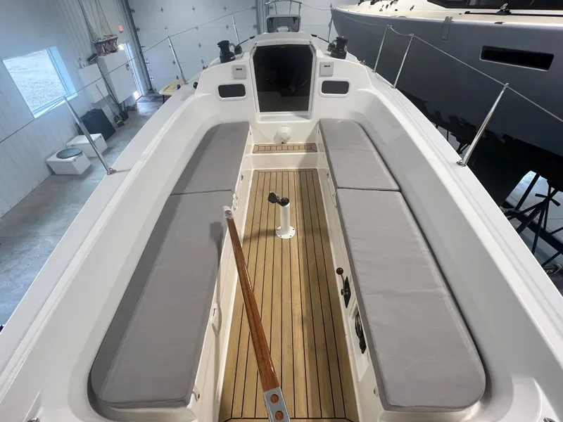 Slide: The Image of 2024 J Boats J/9 sailboat interior with cushioned seating and wooden flooring in a showroom. - 6