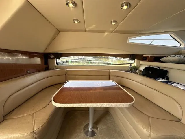 Slide: The Image of Luxurious interior of a 2010 Regal 4080 Flybridge yacht with beige leather seating and wooden table. - 7