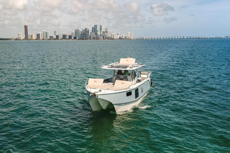 Slide: The Image of 2024 YachtCat 41 cruising on ocean with city skyline in background. - 2