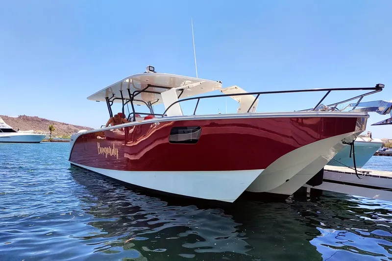 Slide: The Image of Red and white 2024 YachtCat 41 boat docked on calm water under clear blue sky. - 28