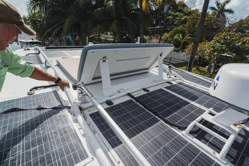 Slide: The Image of 2024 YachtCat 41 with solar panels and open hatch, surrounded by tropical trees. - 7