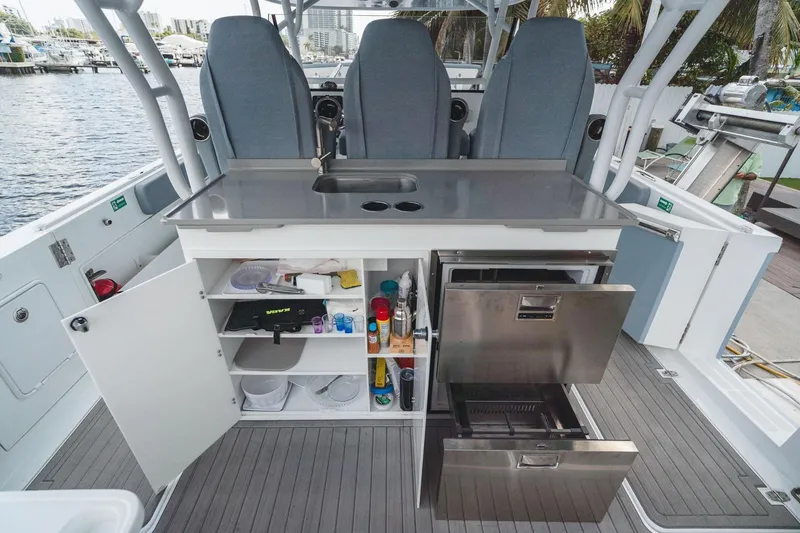Slide: The Image of 2024 YachtCat 41 interior with open storage, stainless steel appliances, and seating by the water. - 9