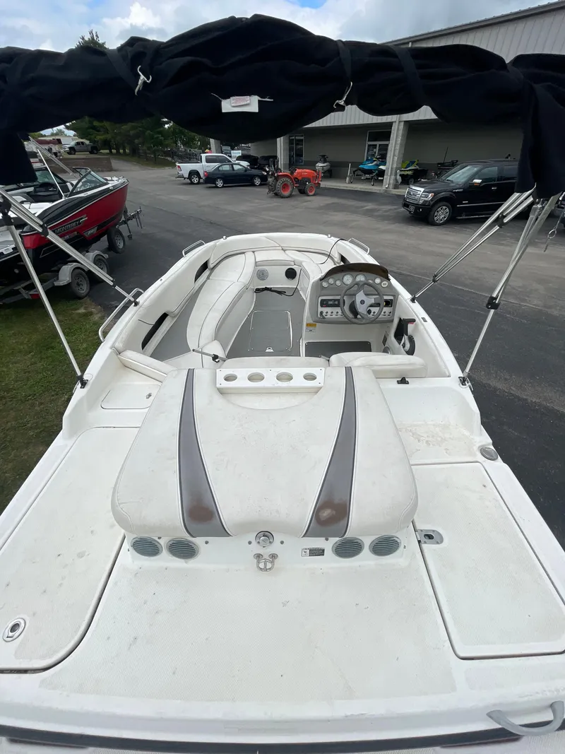 Slide: The Image of 2011 Bayliner 197 boat with white interior and black canopy, docked at a marina. - 11