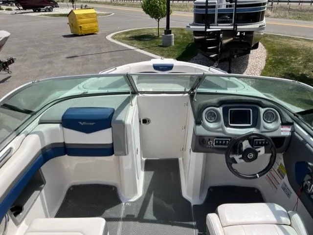 Slide: The Image of 2015 Chaparral 203VR boat interior with steering wheel and dashboard, parked outdoors. - 10