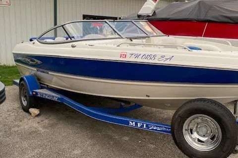 Slide: The Image of 2009 Stingray 195 LX boat on trailer, blue and white design, parked outdoors. - 0