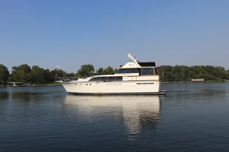 Slide: The Image of 1982 Bertram 58 Fly yacht on calm water with trees in the background. - 0