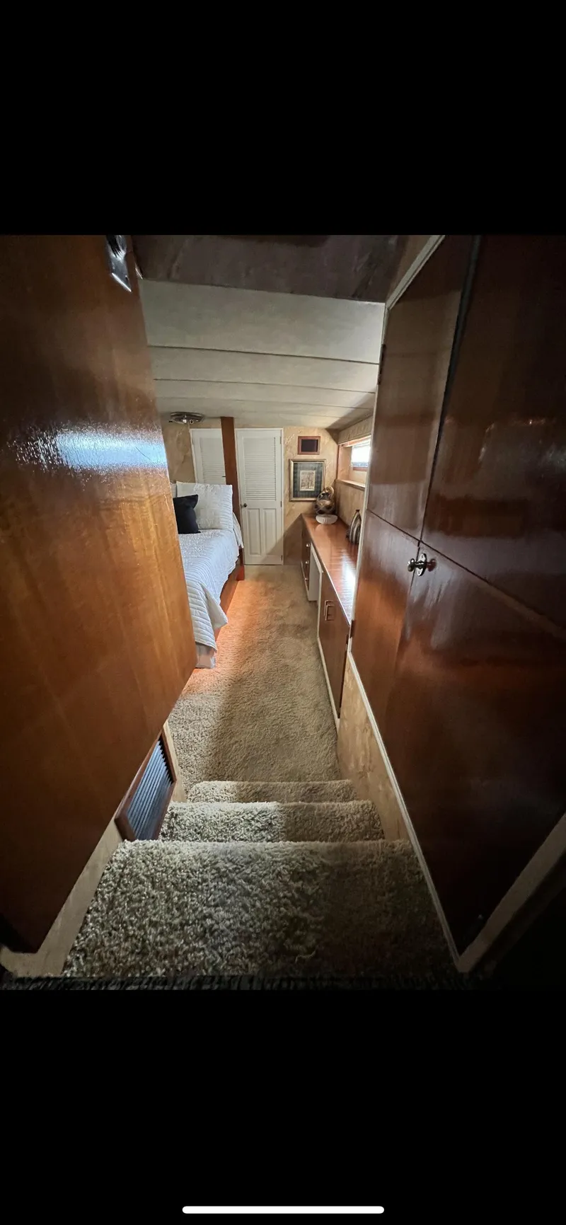 Slide: The Image of Interior view of 1982 Bertram 58 Fly yacht, featuring wooden paneling and carpeted stairs. - 14