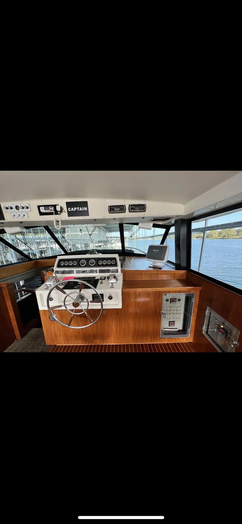 Slide: The Image of 1982 Bertram 58 Flybridge yacht helm with wooden dashboard and modern navigation equipment. - 7