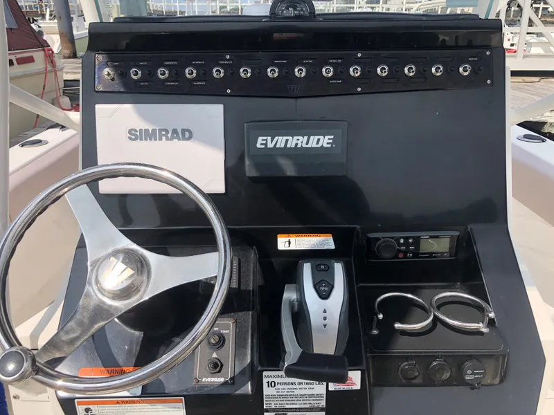 Slide: The Image of 2019 Wellcraft 242 Fisherman boat dashboard with Simrad and Evinrude controls. - 16