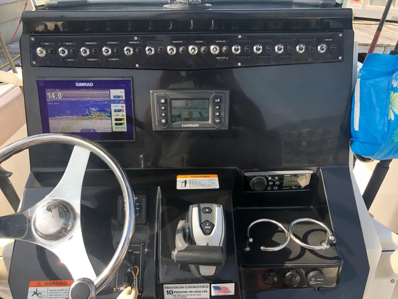 Slide: The Image of 2019 Wellcraft 242 Fisherman boat dashboard with steering wheel, Simrad display, and control panel. - 17