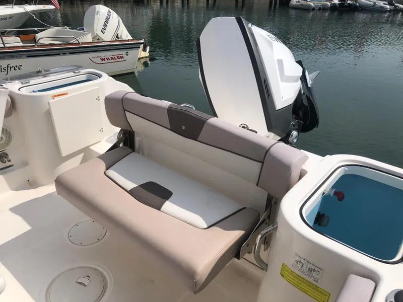 Slide: The Image of 2019 Wellcraft 242 Fisherman boat interior with seating and motor, docked by the water. - 33