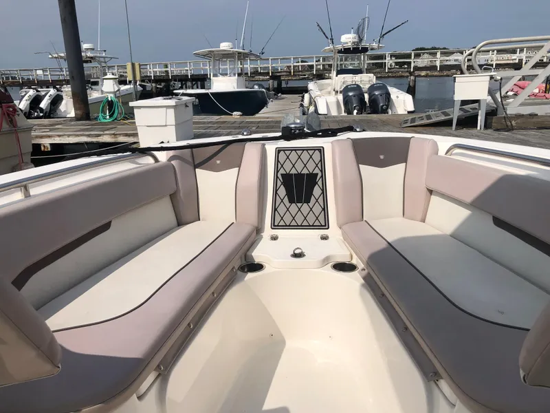Slide: The Image of 2019 Wellcraft 242 Fisherman boat interior with cushioned seating at a marina. - 46