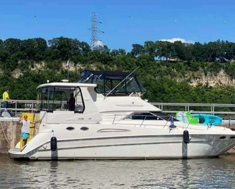 The Image of 1998 Sea Ray 420 Aft Cabin yacht docked by a scenic riverside. - 0
