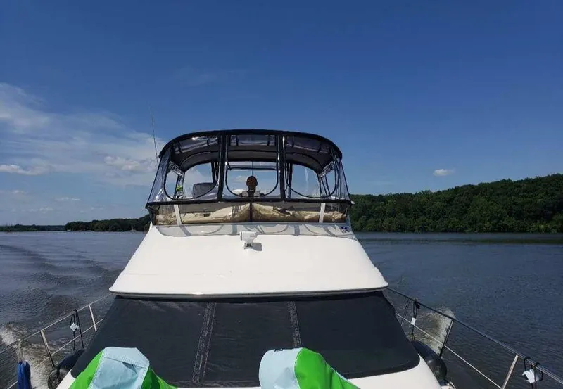 Slide: The Image of 1998 Sea Ray 420 Aft Cabin cruising on a serene lake under a clear blue sky. - 12