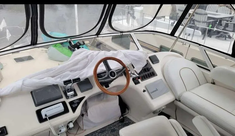Slide: The Image of 1998 Sea Ray 420 Aft Cabin helm with wooden steering wheel and covered controls. - 13