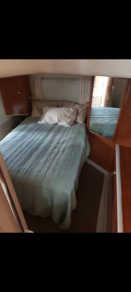 Slide: The Image of 1998 Sea Ray 420 Aft Cabin bedroom with bed, wooden cabinets, and window. - 3
