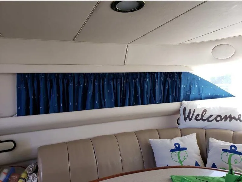 Slide: The Image of 1998 Sea Ray 420 Aft Cabin interior with blue curtains and welcome pillows. - 7