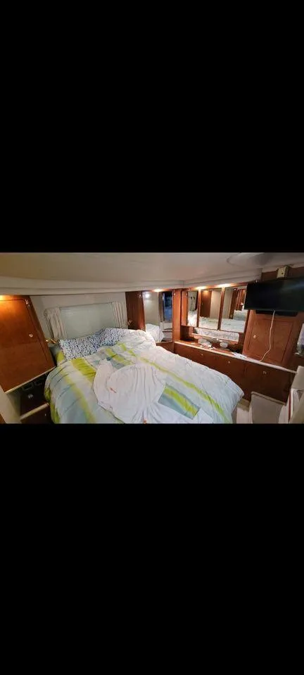 Slide: The Image of 1998 Sea Ray 420 Aft Cabin bedroom with cozy bedding and wooden cabinetry. - 9