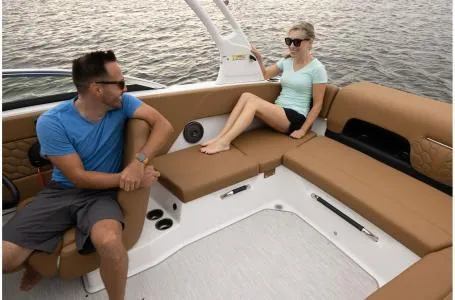 Slide: The Image of 2024 Four Winns H1 OB boat interior with two people relaxing on tan seats. - 30