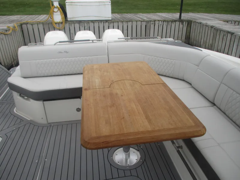 Slide: The Image of 2021 Sea Ray 400 SLX Outboard boat with a wooden table and cushioned seating. - 13