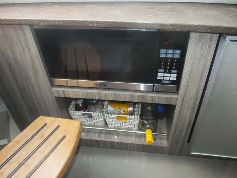 Slide: The Image of Microwave and storage area in 2021 Sea Ray 400 SLX Outboard boat kitchen. - 28