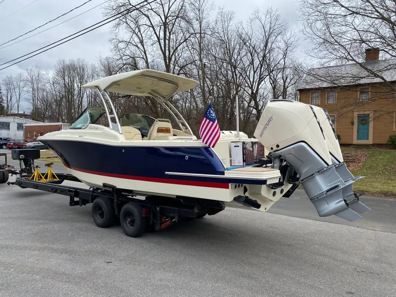 Slide: The Image of 2026 Chris-Craft Calypso 28 boat in a warehouse, featuring sleek design and American flag. - 2
