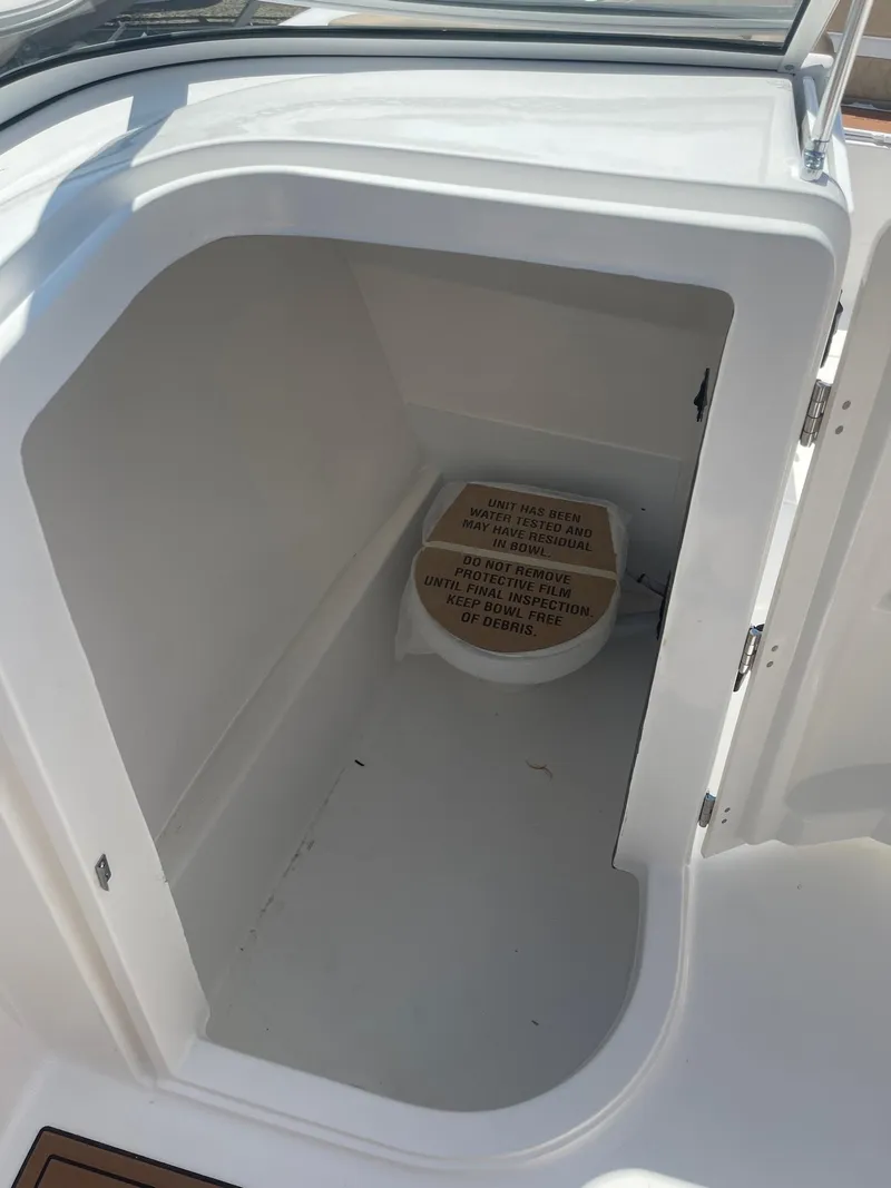 Slide: The Image of 2024 Sea Pro 240 DC Sport boat storage compartment with a portable toilet. - 9