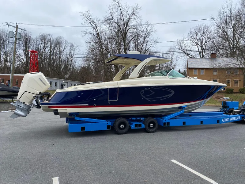 Slide: The Image of 2024 Chris-Craft LAUNCH GT 35 boat on a blue trailer in a parking lot. - 2