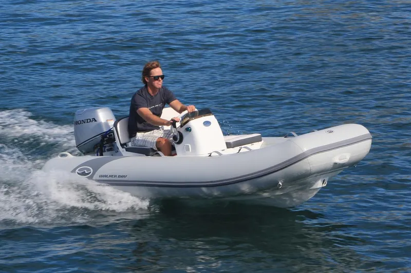 The Image of 2023 Walker Bay 365 STX Deluxe inflatable boat with Yamaha 25HP engine in a garage. - 0