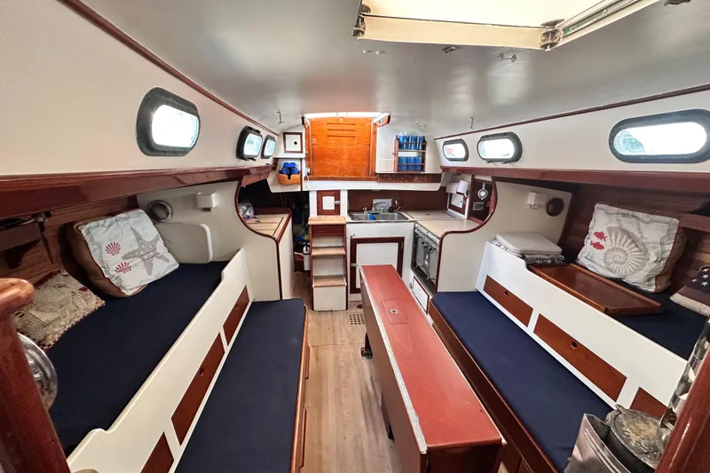 Slide: The Image of Interior of a 1962 Hinckley Bermuda 40 sailboat, featuring cozy seating and a compact kitchen. - 31