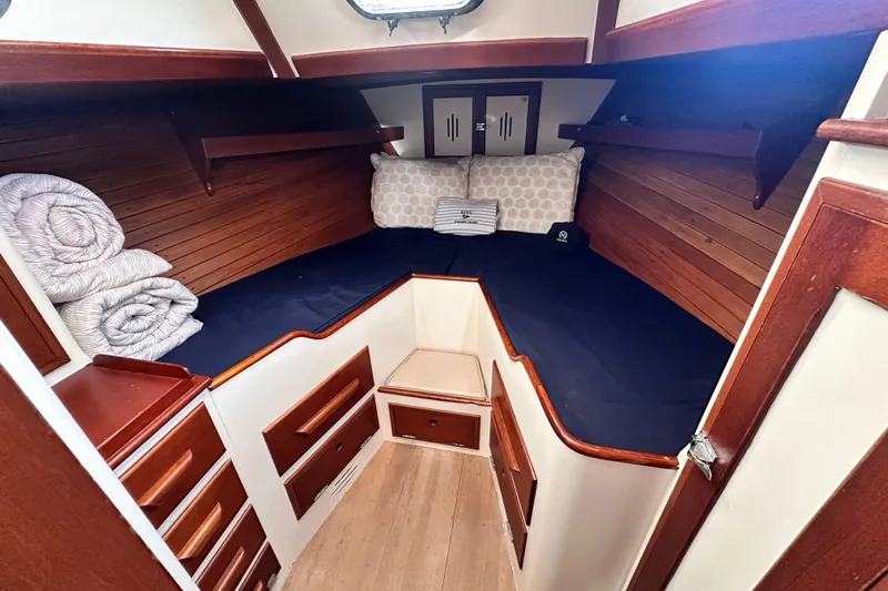 Slide: The Image of Cozy cabin interior of a 1962 Hinckley Bermuda 40 sailboat with wooden accents and bedding. - 32