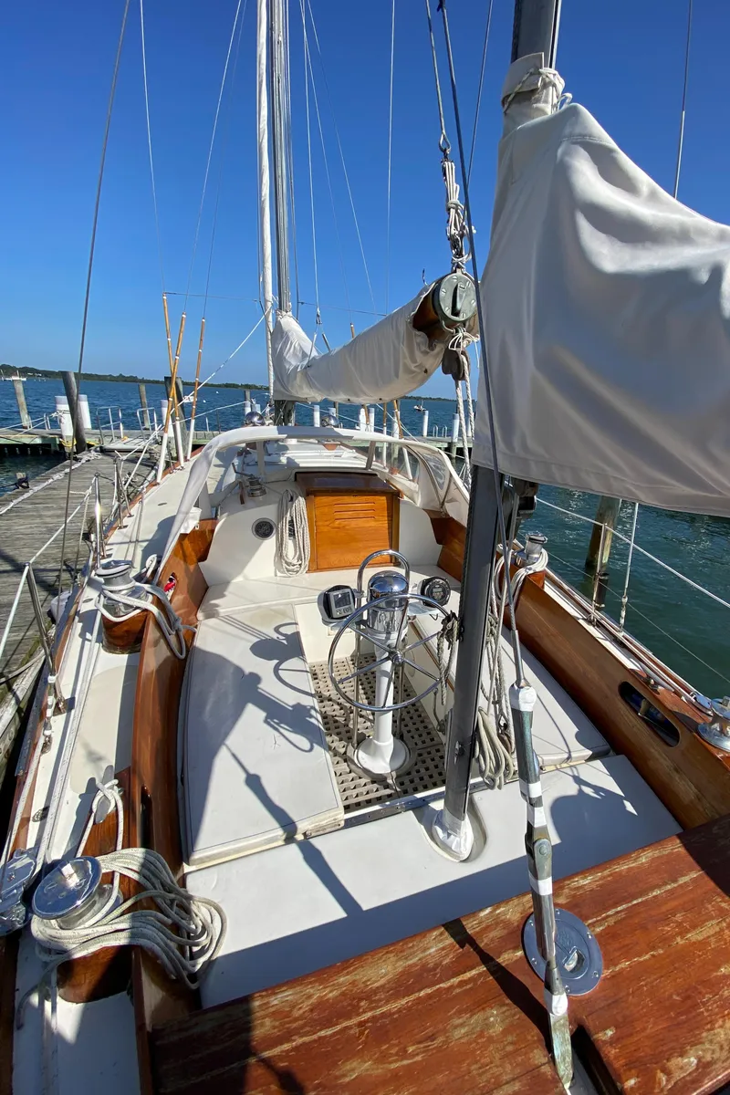 Slide: The Image of 1962 Hinckley Bermuda 40 sailboat with wooden deck and white sails docked at marina. - 7