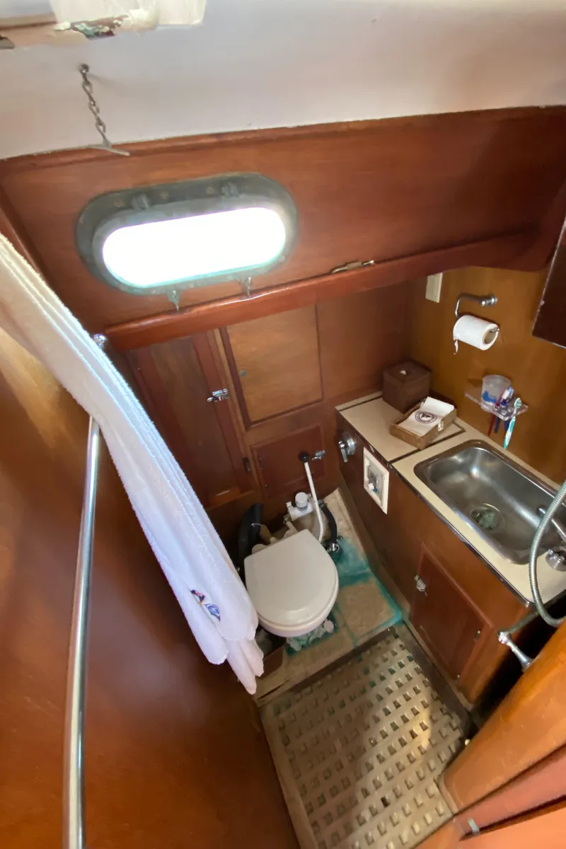 Slide: The Image of Hinckley Bermuda 40 yacht bathroom, featuring a compact toilet, sink, and wooden cabinetry, 1962 model. - 15