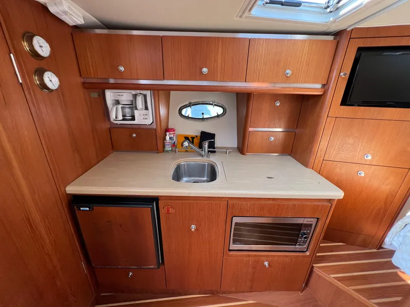 Slide: The Image of 2004 Tiara Yachts 3200 Open galley with sink, microwave, fridge, and storage cabinets. - 19