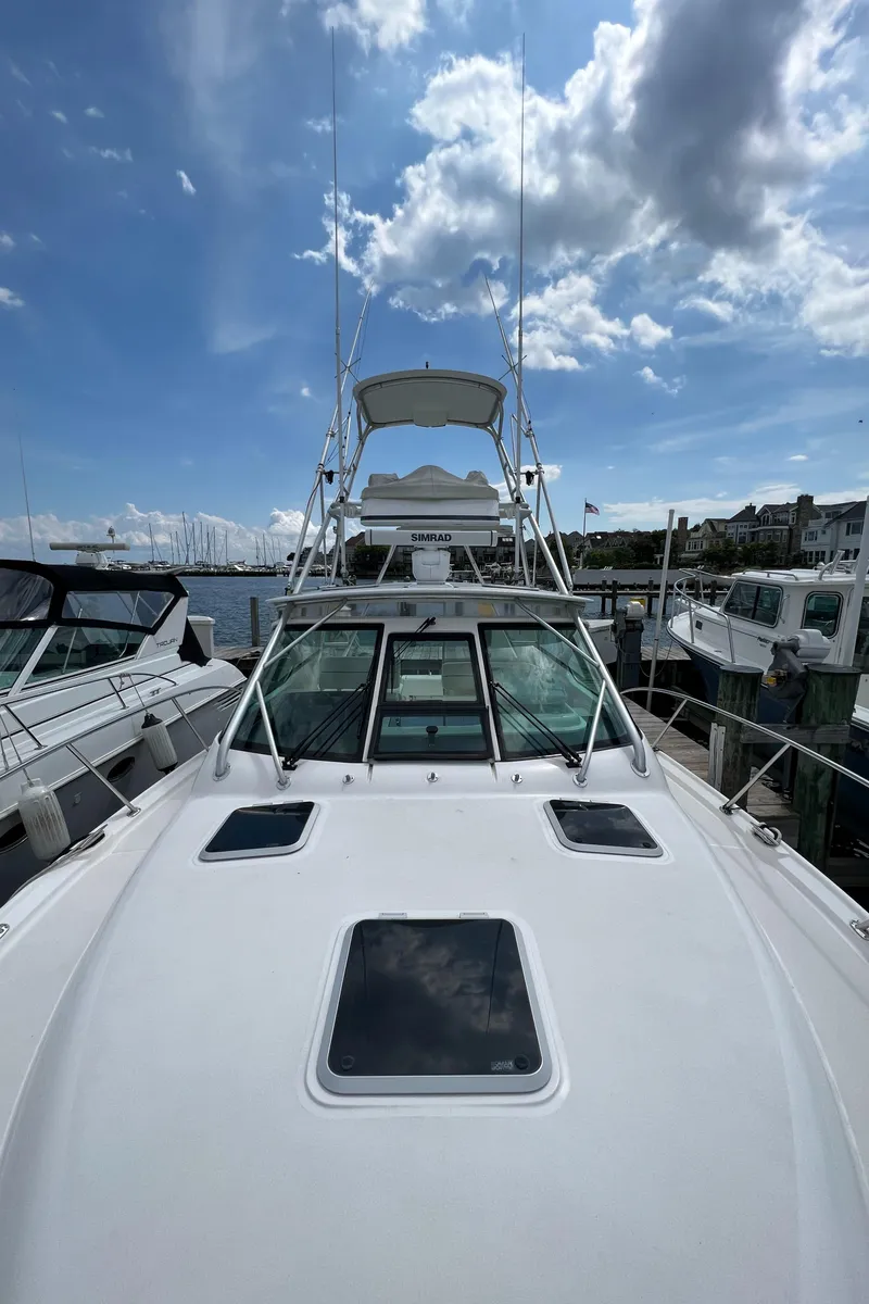 Slide: The Image of 2004 Tiara Yachts 3200 Open docked at a marina under a partly cloudy sky. - 2