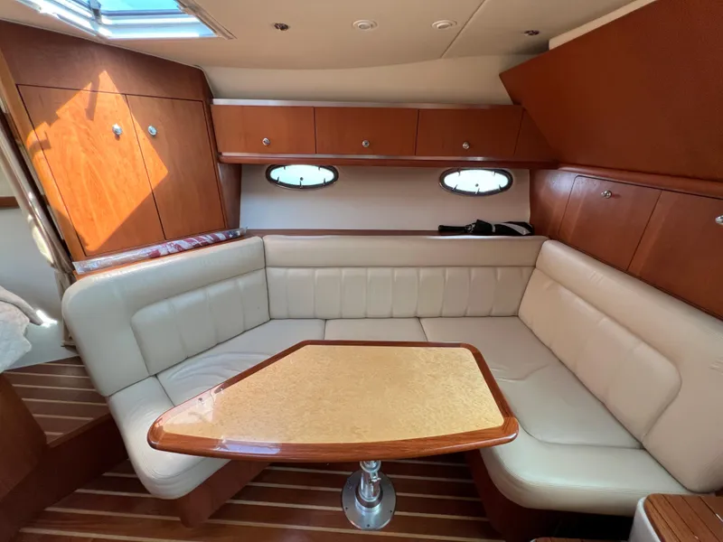 Slide: The Image of 2004 Tiara Yachts 3200 Open interior with L-shaped seating and wooden table. - 21