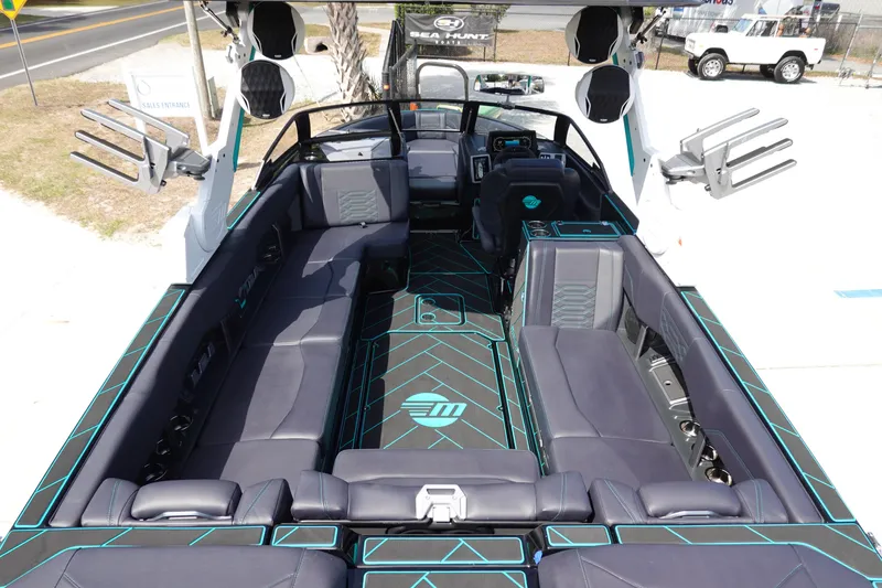Slide: The Image of 2023 Malibu 25 LSV boat interior with black and teal seating and modern dashboard. - 14