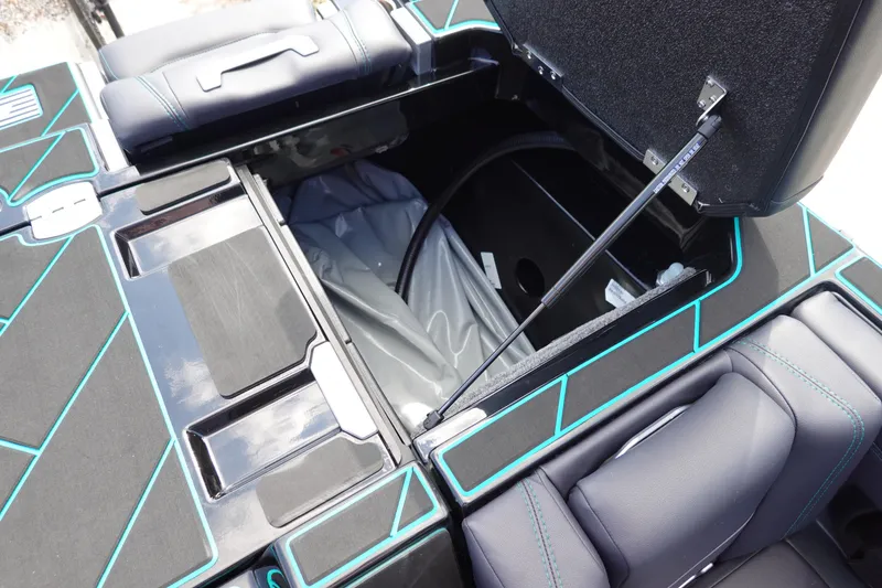 Slide: The Image of Open storage compartment in 2023 Malibu 25 LSV boat with black and teal interior. - 25
