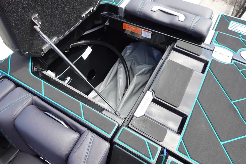 Slide: The Image of 2023 Malibu 25 LSV boat storage compartment with open hatch and black-blue interior. - 26