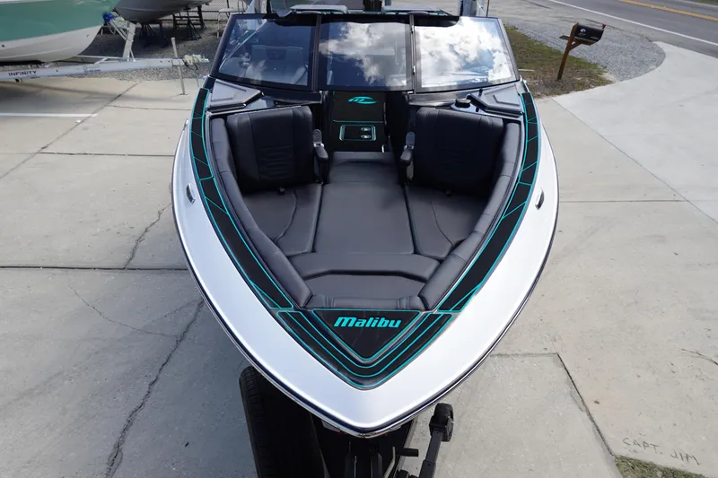 Slide: The Image of 2023 Malibu 25 LSV boat with sleek black and teal interior, docked on concrete. - 3