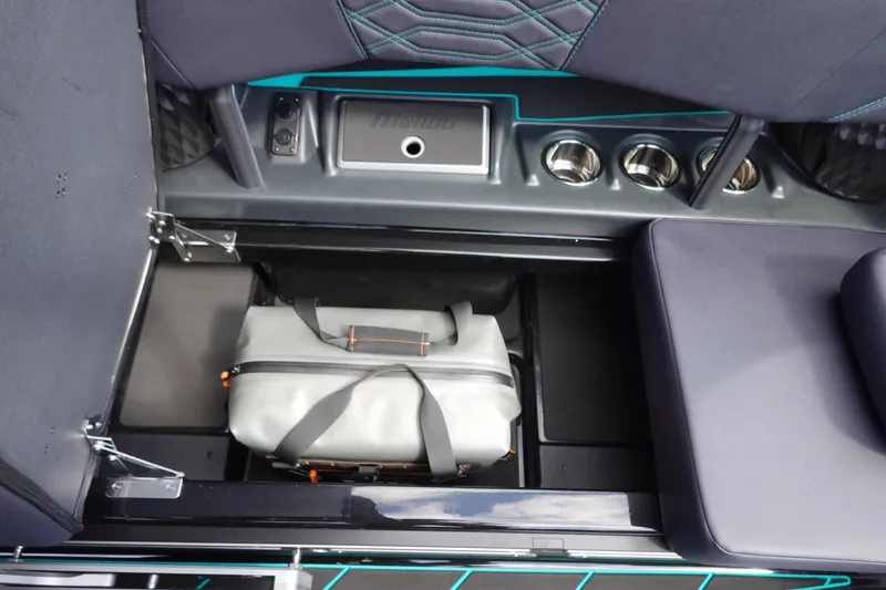 Slide: The Image of 2023 Malibu 25 LSV boat interior storage compartment with bag, cup holders, and seating. - 30